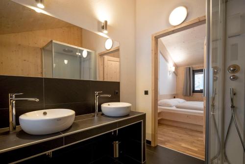 a bathroom with two sinks and a large mirror at Alpenchalets Reiteralm by ALPS RESORTS in Schladming