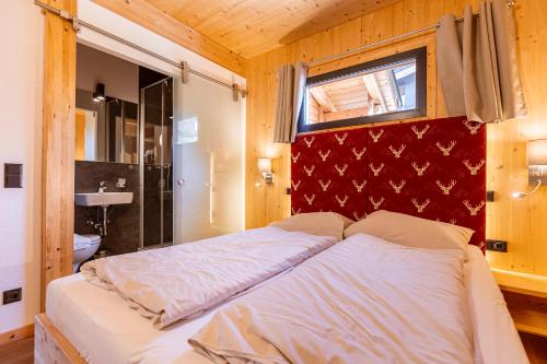 a bed in a room with a red wall at Alpenchalets Reiteralm by ALPS RESORTS in Schladming