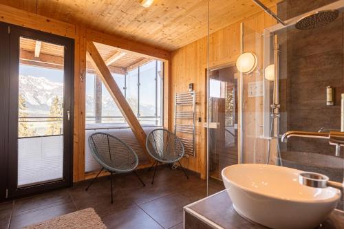 a bathroom with a tub and a sink and chairs at Alpenchalets Reiteralm by ALPS RESORTS in Schladming
