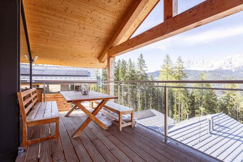 a wooden deck with a picnic table and a bench at Alpenchalets Reiteralm by ALPS RESORTS in Schladming