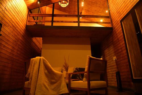 a room with two chairs and a wooden ceiling at Montane Chalet , Sethan in Manāli