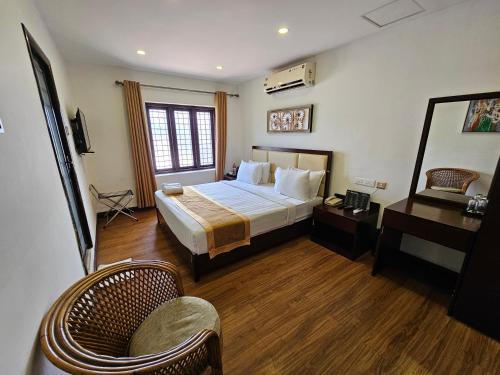 ein Hotelzimmer mit einem Bett, einem Tisch und Stühlen in der Unterkunft ADRAK BOUTIQUE HOTEL in Thiruvananthapuram