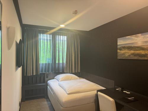 a bedroom with a bed and a desk and window at TIBET HOTEL am Airport Düsseldorf-Ratingen in Ratingen