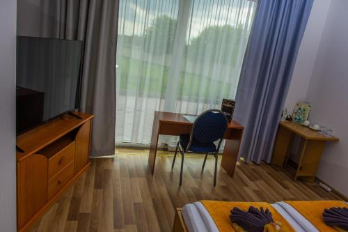 a hotel room with a desk and a tv and a bedroom at Hotel Miodowy in Dzierżoniów
