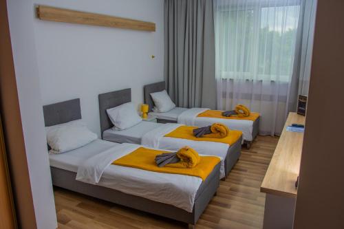 a hotel room with three beds with yellow blankets at Hotel Miodowy in Dzierżoniów