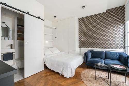 Un dormitorio con una cama y un sofá azul. en La Suite Le Marais, en París
