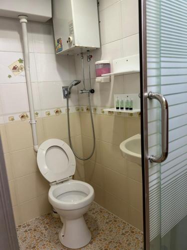 a small bathroom with a toilet and a shower at Holiday Guest House in Hong Kong