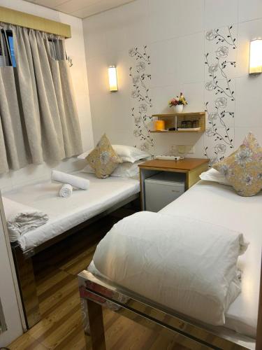 a room with two beds and a table and a desk at Holiday Guest House in Hong Kong