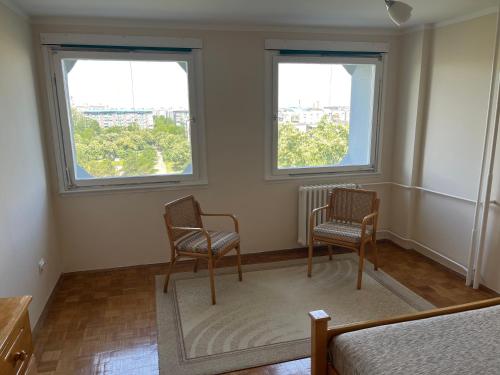 two chairs sitting in a room with two windows at Comfort & Style Panoramic Urban Retreat in Novi Beograd