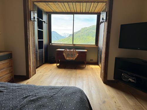 - une chambre avec une grande fenêtre et un bureau avec une chaise dans l'établissement Appartement de standing sur les hauteurs, à Briançon