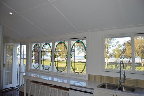 a kitchen with three stained glass windows and a sink at Flinders Seaside Cottage in Brighton