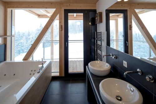 a bathroom with two sinks and a large window at Alpenchalets Reiteralm by ALPS RESORTS in Schladming