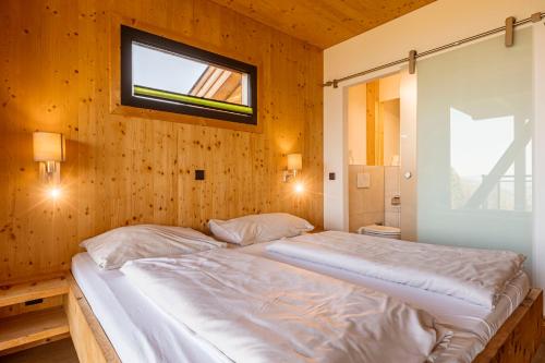 a bedroom with two beds in a wooden wall at Alpenchalets Reiteralm by ALPS RESORTS in Schladming