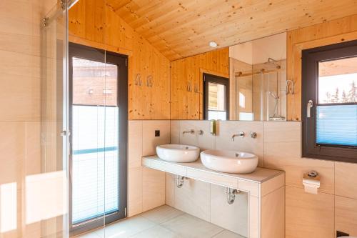a bathroom with two sinks and a mirror at Alpenchalets Reiteralm by ALPS RESORTS in Schladming