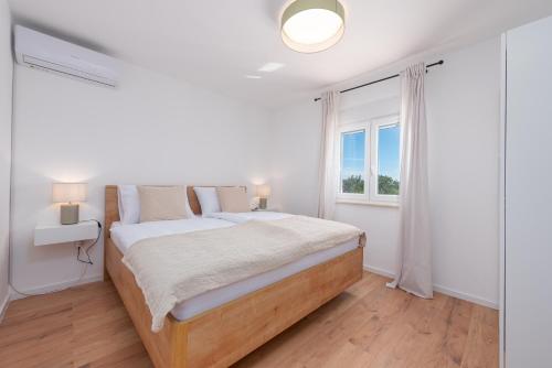 een witte slaapkamer met een bed en een raam bij Holiday Home LaMar - with heated pool and whirlpool in Raštević