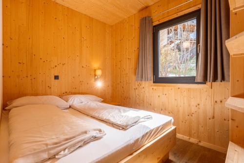 a bed in a wooden room with a window at Alpenchalets Reiteralm by ALPS RESORTS in Schladming