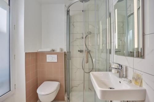 uma casa de banho com um chuveiro, um lavatório e um WC. em Hipotel Paris Gare du Nord Merryl em Paris