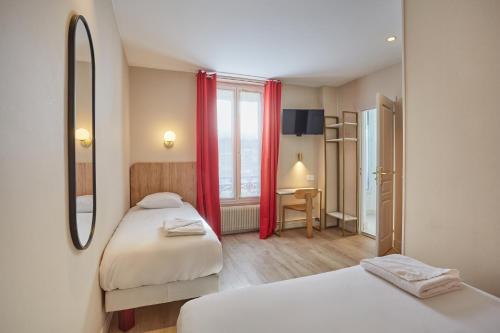 a bedroom with two beds and a desk and a window at Hipotel Paris Gare du Nord Merryl in Paris