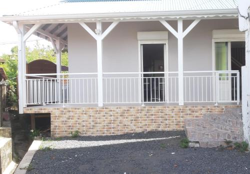 ein Haus mit einer weißen Veranda und einer Ziegelwand in der Unterkunft Ka Villa Location in Pointe-Noire