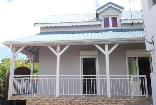 Dieses weiße Haus verfügt über eine Veranda und einen Balkon. in der Unterkunft Ka Villa Location in Pointe-Noire