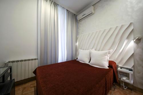a bedroom with a bed with two pillows and a window at Hostal Las Fuentes in Madrid