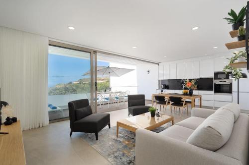 a living room with a couch and chairs and a kitchen at Hibisco is a modern apartment, 5min walk to beach in Luz