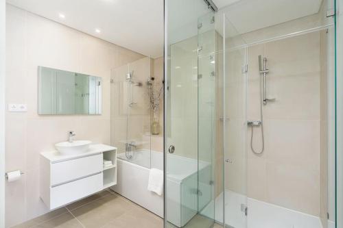 a bathroom with a glass shower and a sink at Hibisco is a modern apartment, 5min walk to beach in Luz