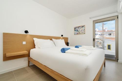 a large white bed in a room with a window at Hibisco is a modern apartment, 5min walk to beach in Luz