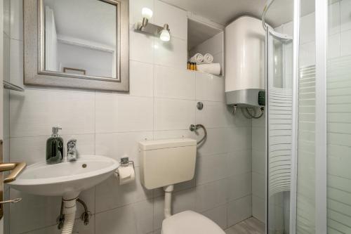 a white bathroom with a toilet and a sink at Studio Amore in Dubrovnik