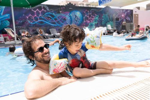 a man and a child sitting in a swimming pool at Abraham Eilat in Eilat