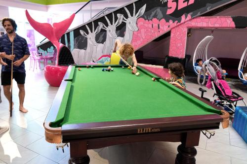 a woman and two children playing with a pool table at Abraham Eilat in Eilat