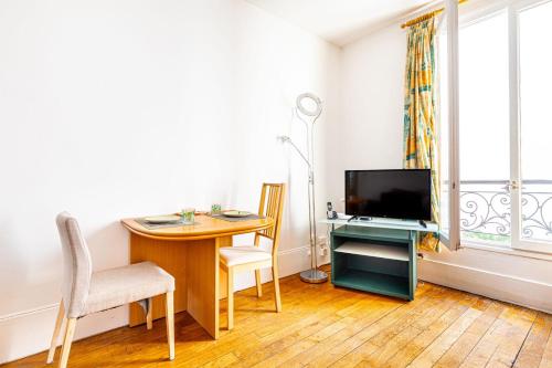 sala de estar con mesa, TV y escritorio con mesa en GuestReady - Modernity and comfort in Plaisance, en París