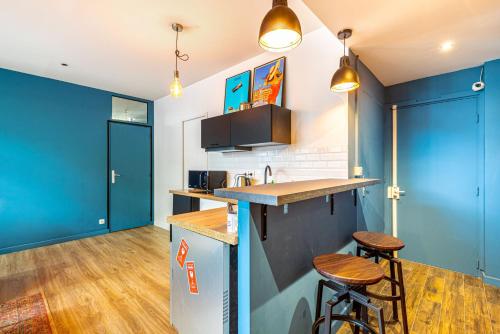 - une cuisine avec des murs bleus et des tabourets de bar dans l'établissement GuestReady - Apt de Charme près de la Tour Eiffel, à Paris
