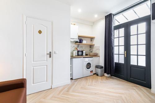 une cuisine blanche avec une porte noire et une buanderie dans l'établissement GuestReady - Charming Getaway in Le Marais, à Paris