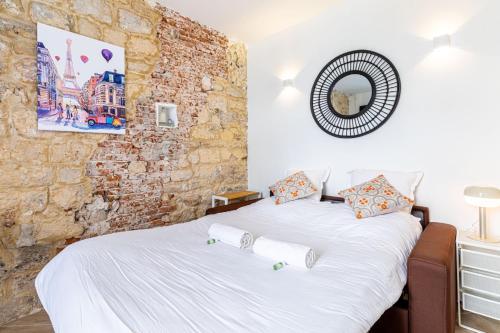 une chambre avec deux lits et un mur de briques dans l'établissement GuestReady - Charming Getaway in Le Marais, à Paris