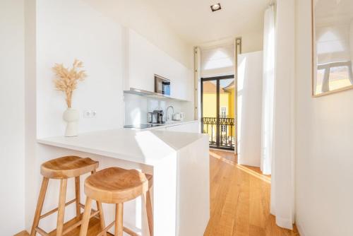 a kitchen with a counter and two stools at GuestReady - Conde das Alcáçovas in Paço de Arcos