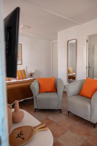 a living room with two chairs and a tv at Los Bungalows Del Arenal in Jávea