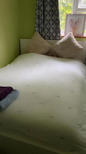 een wit bed in een slaapkamer met een raam bij 6 badger way in Hatfield