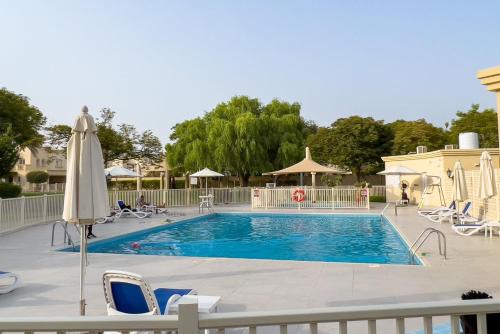 a large swimming pool with chairs and a umbrella at GuestReady - Springs Serenity near Golf Club in Dubai