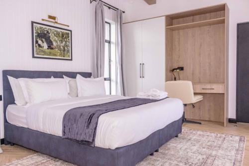 a bedroom with a large bed and a desk at Tufaha Resort in Nanyuki