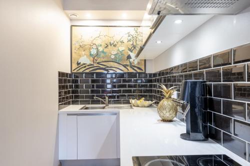 une cuisine avec un évier et un tableau mural. dans l'établissement Charmant studio au centre ville, à Bordeaux