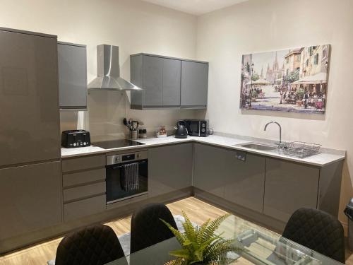 a kitchen with gray cabinets and a table with chairs at Flat 2 ,559 Wimborne Road in Bournemouth