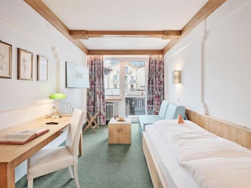 a hotel room with a bed and a desk and a window at Genuss - und Vitalhotel Moisl in Abtenau