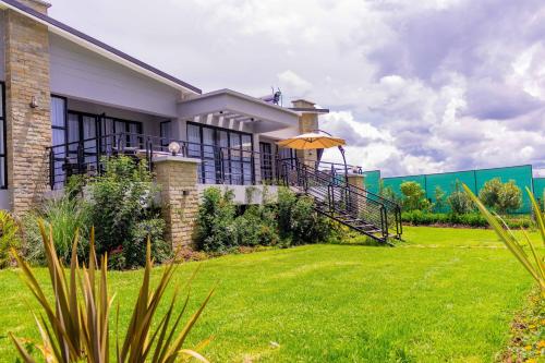 a house with an umbrella and a grass yard at Tufaha Resort in Nanyuki