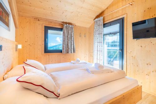 a bed in a wooden room with a window at Alpenchalets Reiteralm by ALPS RESORTS in Schladming