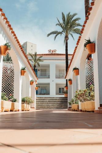 a boardwalk in front of a building with palm trees at Los Bungalows Del Arenal in Jávea