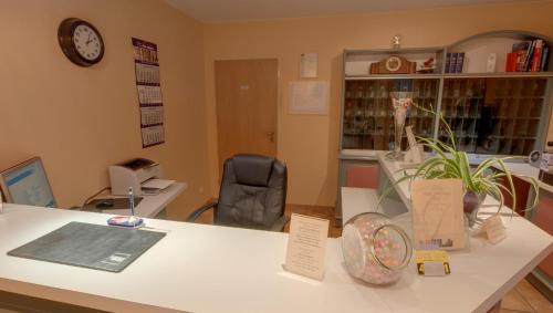 a room with a desk with a clock and a chair at Hotel Garni Stadt Friedberg in Friedberg