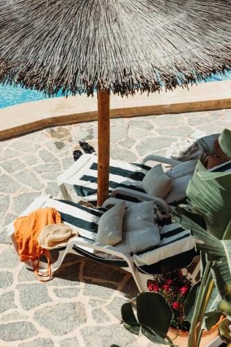 a group of lounge chairs and an umbrella on a beach at Los Bungalows Del Arenal in Jávea
