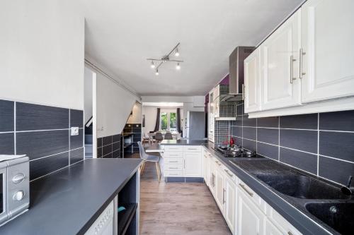 une cuisine avec des armoires blanches et des comptoirs noirs dans l'établissement Le Clos des Layottes, à Ladoix Serrigny