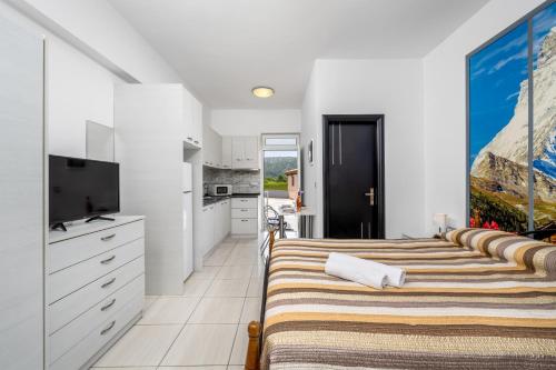 a room with three beds and a tv and a kitchen at Pervolia Studios Near Airport in Kremasti